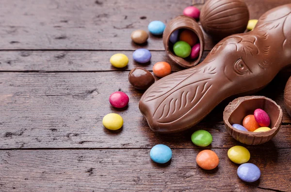 Chocolate easter eggs and sweets on wooden background — Stock Photo, Image