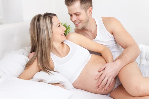 Encantados padres jóvenes en la cama esperando un bebé —  Fotos de Stock