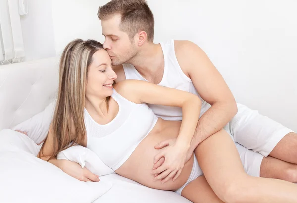 Jovens pais encantados na cama esperando um bebê — Fotografia de Stock