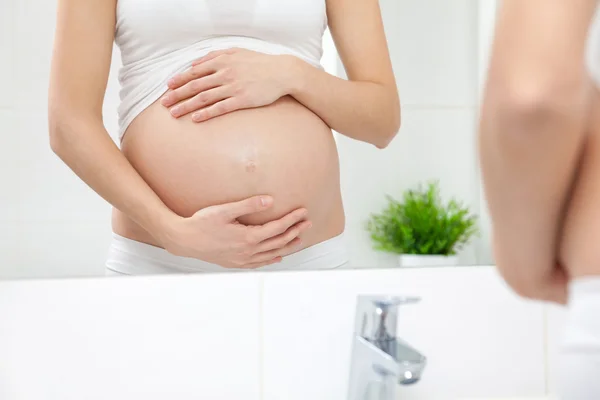 Pregnant woman in bathroom mirror — Stock Photo, Image