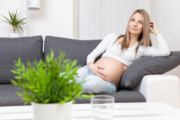 Krásná těhotná žena relaxuje doma — Stock fotografie