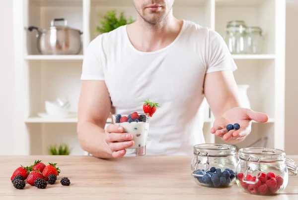 Homem com delicioso iogurte com bagas frescas — Fotografia de Stock