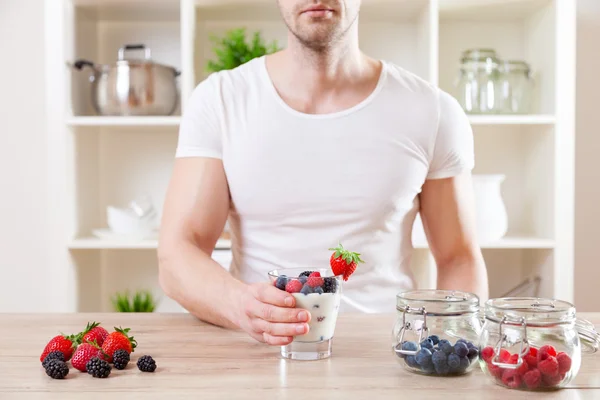 Homem com delicioso iogurte com bagas frescas — Fotografia de Stock