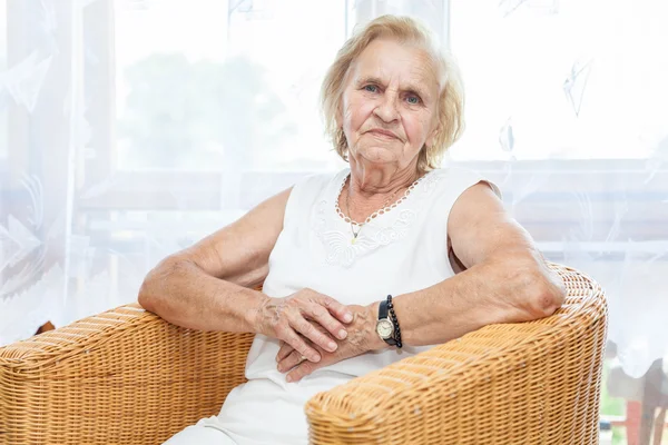 Porträtt av en äldre dam sitter i en stol — Stockfoto