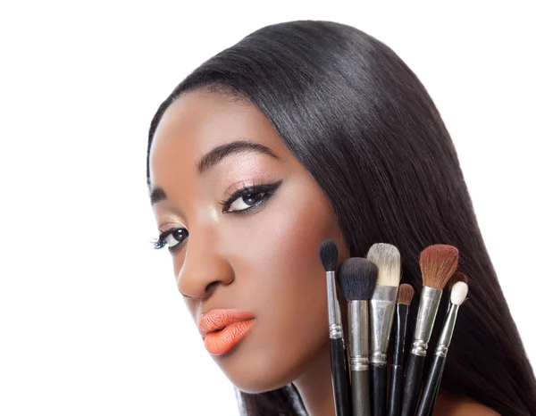 Mulher negra com cabelo liso segurando pincéis de maquiagem — Fotografia de Stock