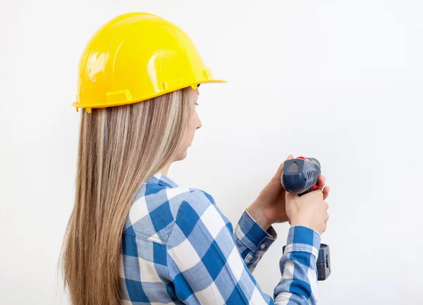 Jonge vrouw boren van een gat in de muur — Stockfoto