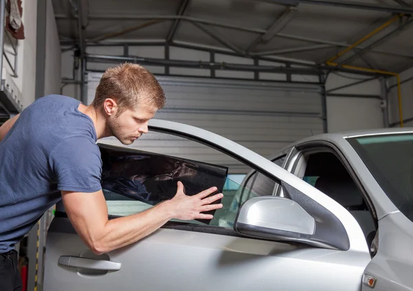 Aplicando lámina de teñido a una ventana del coche Imagen De Stock