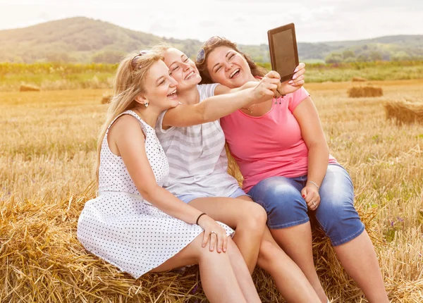 Группа друзей в поле фотографируется с планшетом — стоковое фото