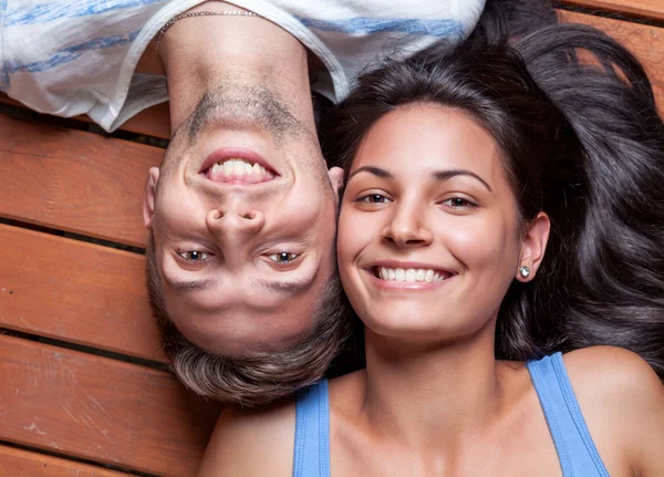 Jovem casal feliz deitado em um chão de madeira — Fotografia de Stock