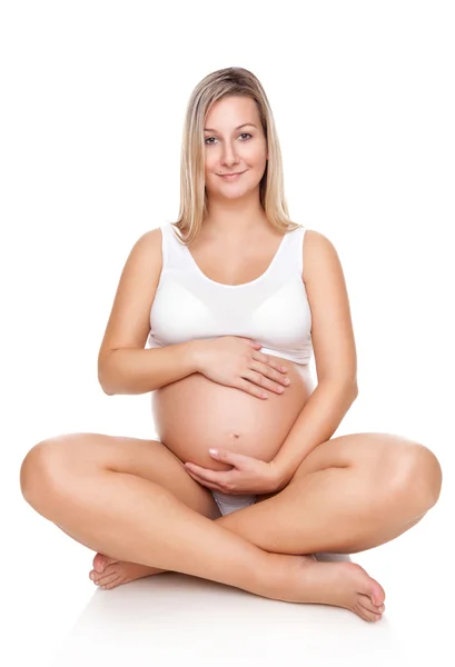 Portrait of a pregnant woman sitting on floor and holding belly — Stock Photo, Image