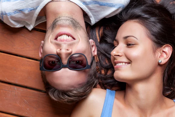 Happy young couple lying on a wooden floor — Stock Photo, Image