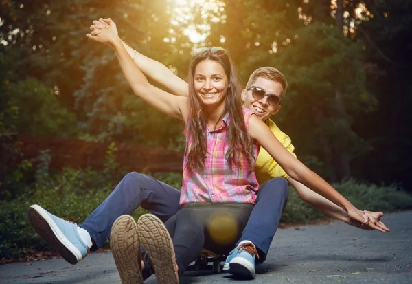 Pareja joven enamorada sentada en un monopatín al aire libre —  Fotos de Stock