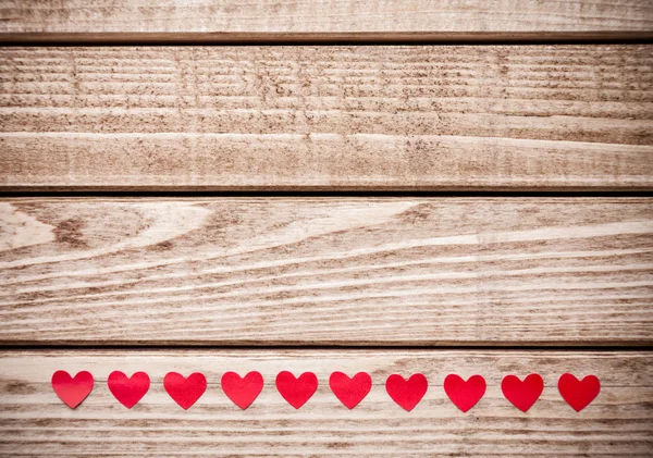 Multiple small red hearts on wooden background — Stock Photo, Image