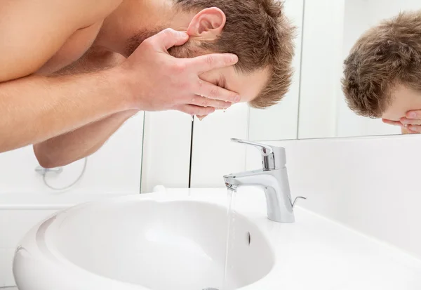 Homem lavando rosto no banheiro dissipador — Fotografia de Stock