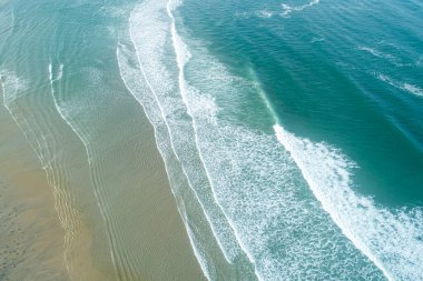 - Altı. Geniş kumlu bir sahil ve turkuaz okyanus dalgalarının hava manzarası..