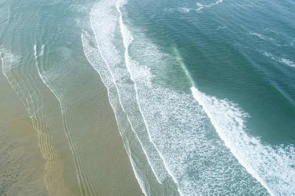 - Altı. Geniş kumlu bir sahil ve turkuaz okyanus dalgalarının hava manzarası..