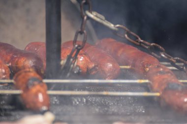 Ateşin üstünde ızgara yapan baharatlı sosisler Lezzet Konsepti
