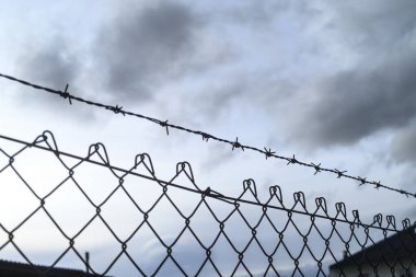 Dikenli tel ve karanlık atmosferle endüstriyel çevre koruması