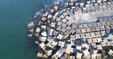 Beton dalgalar üzerinde kırmızı ve beyaz deniz fenerinin insansız hava aracı görüntüsü