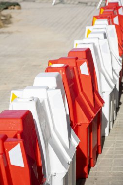 Şehrin kaldırımında uzun bir sıra kırmızı beyaz plastik bariyer var.