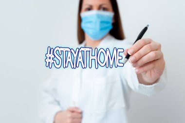 Hashtag 'in evde kaldığını gösteren kavramsal el yazısı. Sosyal medyada Coronvirus salgını laboratuvar teknisyeninin kağıt aksesuarlarıyla ilgili bir trend etiketini gösteren iş fotoğrafı