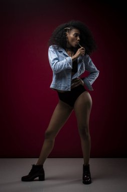 Kot ceketli, siyah iç çamaşırlı, lolipop yalayan seksi bir esmerin dikey portresi.