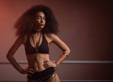 Siyah iç çamaşırlı kıvırcık saçlı, seksi ve kendinden emin bir esmerin yakın portresi.