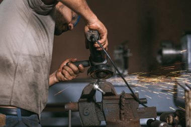 Adam mekanik atölyesinde aletleriyle çalışıyor.