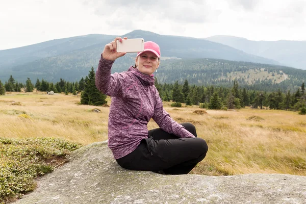 Woman hiker taking photo selfie with smart phone at mountain krkonose — Stock Photo, Image