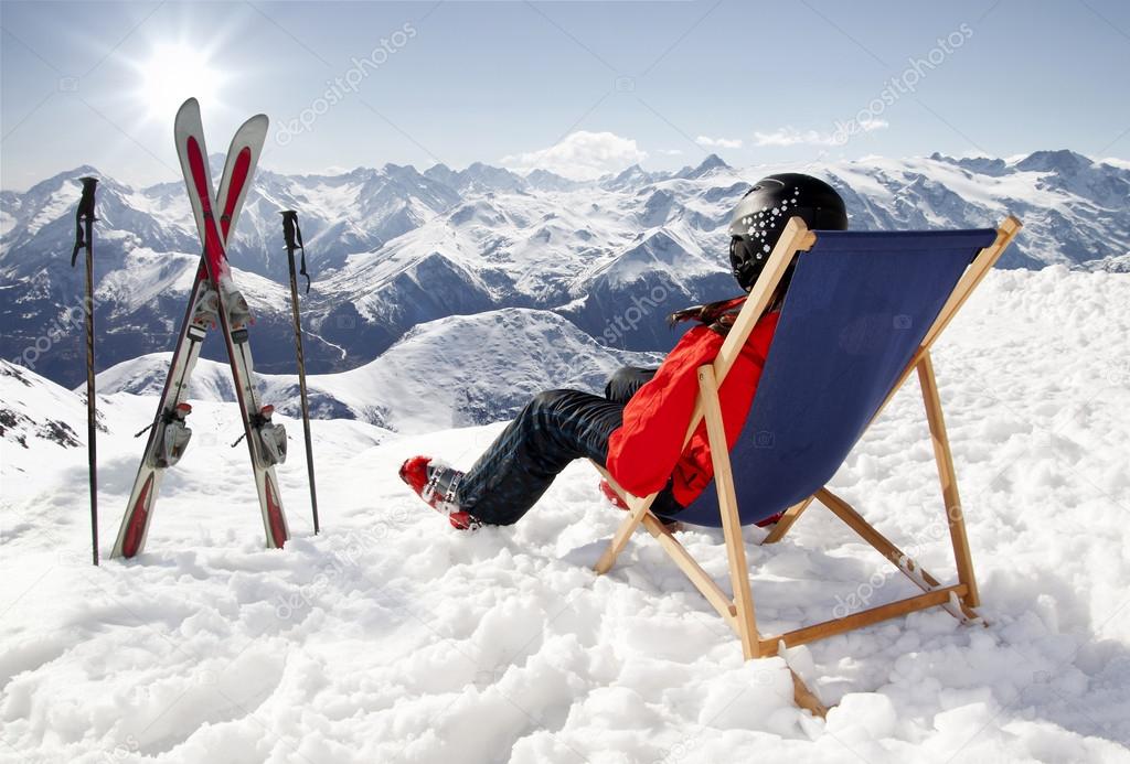 Women at mountains in winter lies on sun-lounger