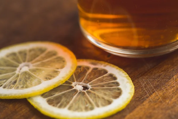 Перспективный вид на черный чай с лимоном в чашке и на деревянный стол доски — стоковое фото