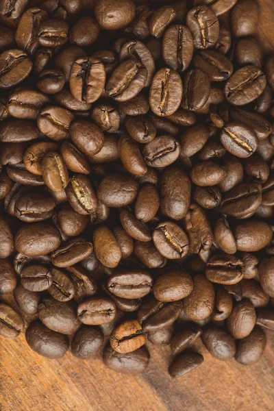 Brown coffee beans, closeup of macro coffee beans for background and texture. On brown wooden board. — Stock Photo, Image