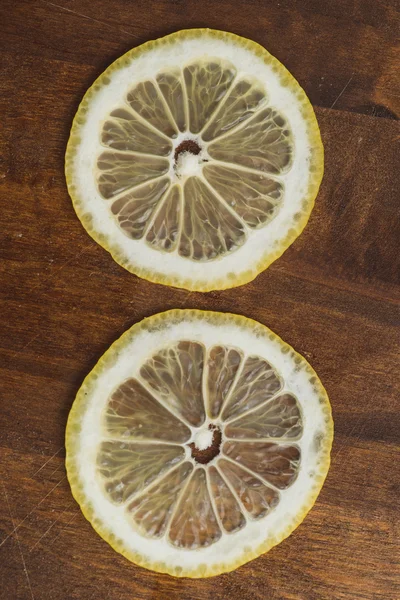 Two thin slices Fresh Lemon on Wood Table Background, Rustic Style. — Stock Photo, Image