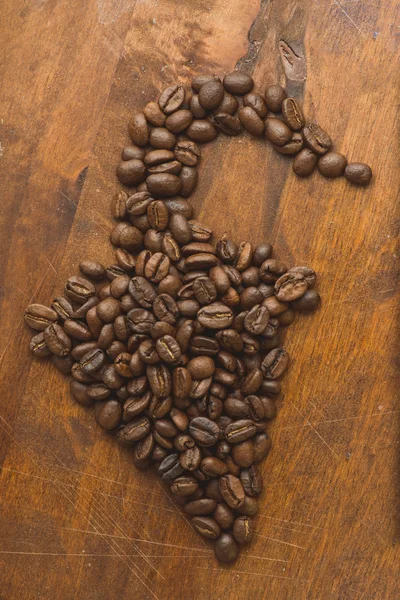후추, 배경과 텍스처에 대 한 매크로 커피 콩의 모양에 갈색 커피 콩. 갈색 나무 보드에. — 스톡 사진