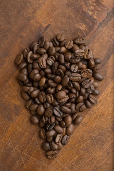 드롭, 배경과 텍스처에 대 한 매크로 커피 콩의 모양에 갈색 커피 콩. 갈색 나무 보드에. — 스톡 사진
