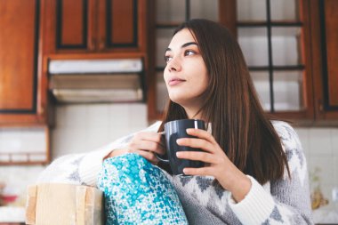 Evde kahve içen genç bir kadın..