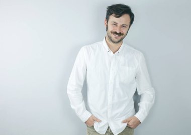 Gri arka plandaki yakışıklı genç adam kameraya bakıyor..