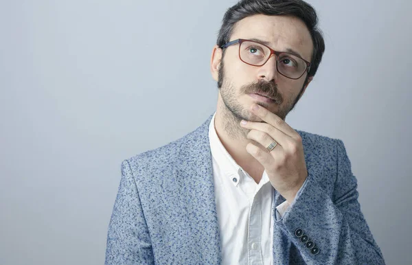 Gri arka planda duran düşünceli genç adam..