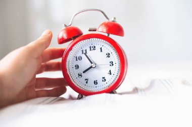 Zaman optimizasyonu konsepti. Yatak arka planında alarmlı saati tutan kadın, görüntüyü kapat