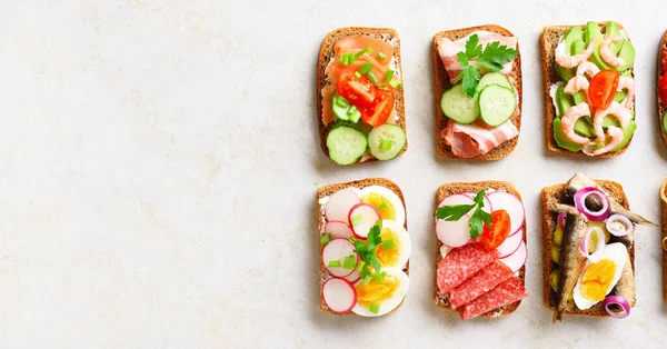 Set of different sandwiches with meat, vegetables, seafood. Assortment open sandwiches on light stone background with free text space. Top view, flat lay. — Stock Image Set Different Sandwiches Meat Vegetables Seafood Assortment Open Sandwiches Light Stock Photo