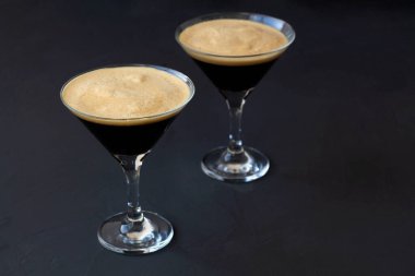 Kahve çekirdeğiyle süslenmiş espresso martini kokteyli. Siyah arka planda iki martini bardağı. Alkollü. kopyalama alanı. en üstteki görünüm