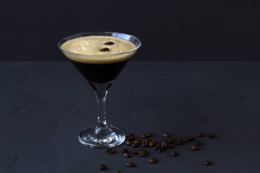 Kahve çekirdeğiyle süslenmiş espresso martini kokteyli. Siyah arka planda martini bardağı. Alkollü. Boşluğu kopyala.