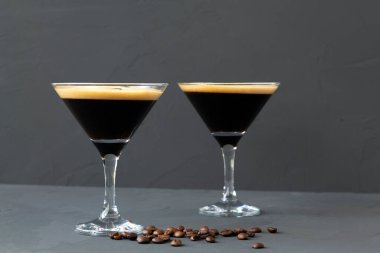 Kahve çekirdeğiyle süslenmiş espresso martini kokteyli. Siyah arka planda iki martini bardağı. Alkollü. Boşluğu kopyala.