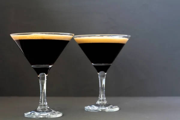 Espresso Martini cocktail garnished with coffee beans on dark table. Two Martini glasses on a black background. alcohol drinks. copy space.