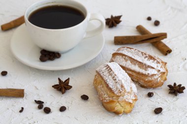 Arka planda bir tabakta vanilyalı ekler. Kahve çekirdekli kahve fincanı ve anason yıldızı, beyaz masada tarçın çubukları. kopyalama alanı. Geleneksel Fransız Lezzetli Tatlı.