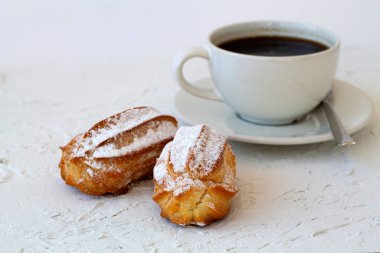 Masadaki vanilyalı ekler. Beyaz arka planda bir fincan sade kahve. Geleneksel Fransız tatlısı. Boşluğu kopyala