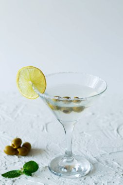 Barda margarita kokteyli. Yeşil naneli ve beyaz arkaplanlı zeytinli martini bardağı. Limonlu martini için bardaklar. kopyalama alanı. Dikey. Alkollü. en üstteki görünüm