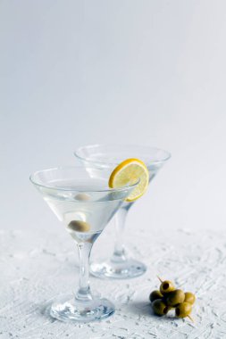 Alkollü. Barda margarita kokteyli. Beyaz arka planda iki martini bardağı ve zeytin. Zeytinli martini için bardaklar. kopyalama alanı. dikey