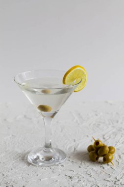 Barda margarita kokteyli. Beyaz arka planda zeytinli martini bardağı kokteyli. Limonlu martini için bardaklar. kopyalama alanı. Alkollü. dikey