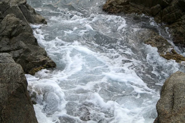 岩の上を流れる水 岩の上で波がクラッシュ 地中海の美しい景色をご覧ください ビーチでは 水と曇りの空の背景に大きな石 岩の上を流れる水は — ストック写真